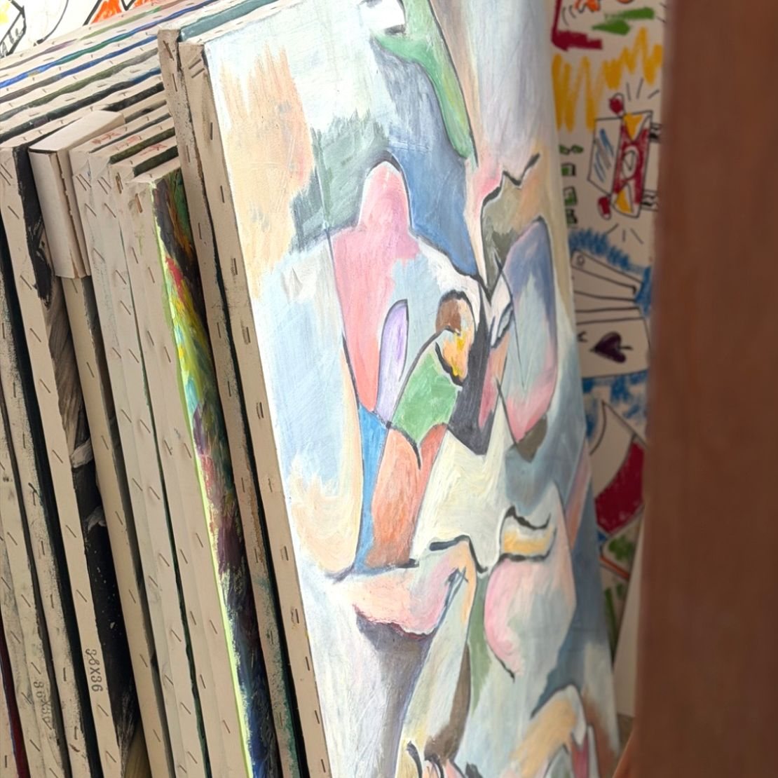 Canvases stacked against the studio wall beside an easel